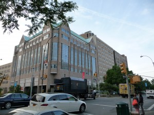 Large neo-modern 8 story bldg at busy street corner.