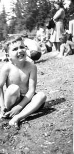 Very young boy in suit sitting on beach frowing