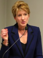 Carly_Fiorina_in_dark blue talking into a mic.