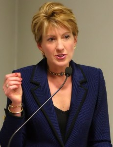 Carly_Fiorina_in_dark blue talking into a mic.