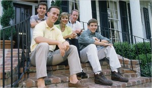 Cleft palate P Manning (l) sitting on steps with family or origin, incl QB dad (ctr) & QB bro (r).