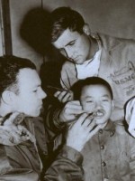 Blsck n white photo of Dr. Millard (left) examining Asian cleft lip patient.