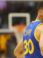 BBall great Steph Curry in blue jersey looking over shoulder.