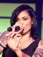 Dark-haired Kehlani, a cyberbullying victim, sings with mic.