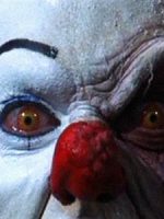 Close up of white-faced, red-nosed clown without facial symmetry.