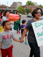 Woman holding hand of young child marching to end 'school-to-prison pipeline.'