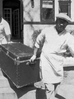 Black trunk of privileged killer Einhorn. Trunk with body being carried by two men.