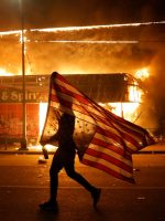 An upside down flag, a sign of distress, next to a burning building on Thursday, May 28, 2020, in Minneapolis. AP /Cortez